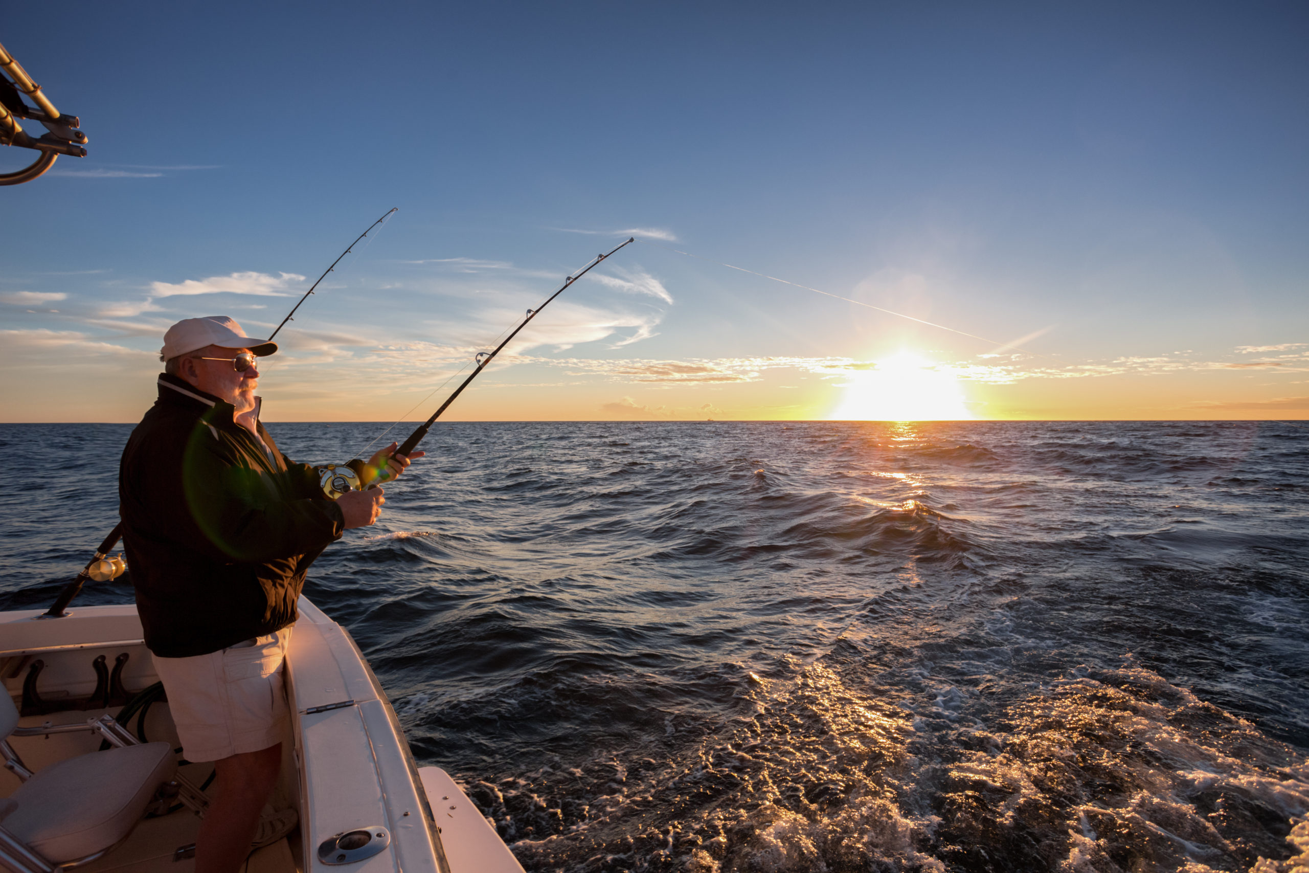 Fisherman angling on a deep sea fishing charter boat in Rockport TX at sunset